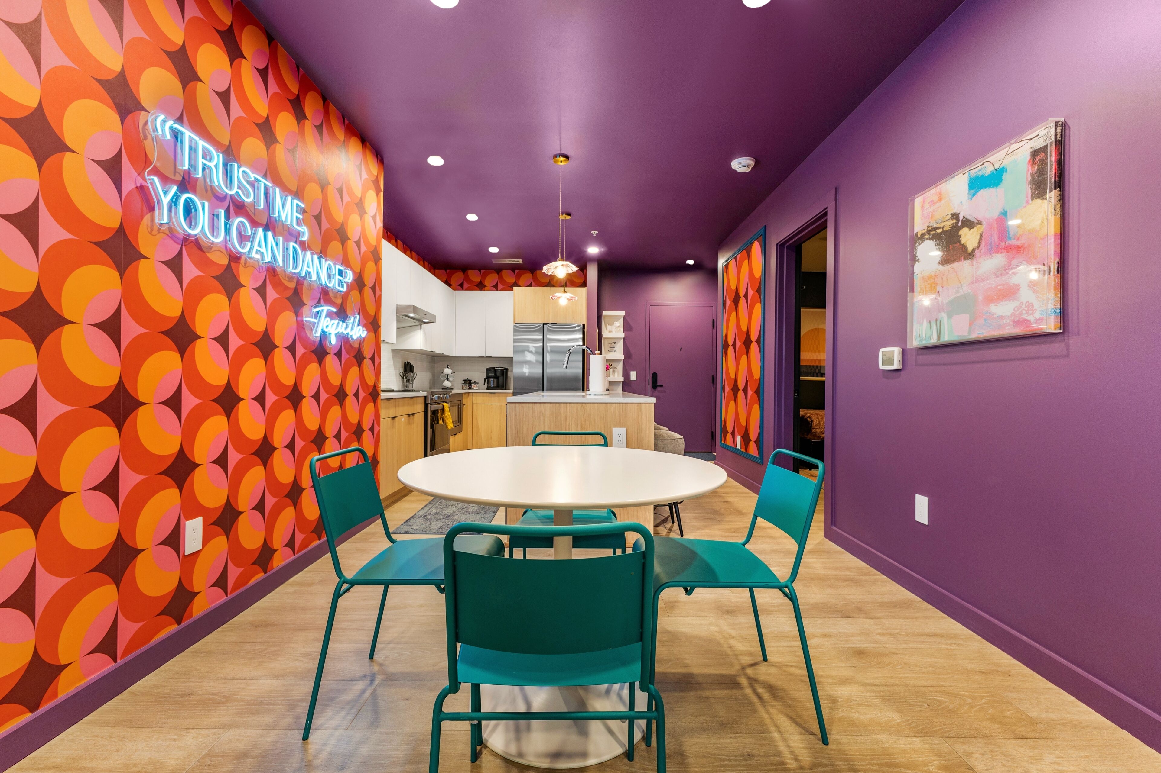Una cocina moderna con comedor que incluye una mesa redonda y sillas color turquesa.