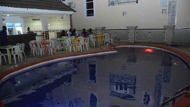 An indoor swimming pool with clear water, surrounded by white plastic chairs and tables. - Highcon Hotel and Suite (Omu-Aran)
