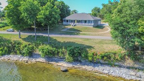 A two-story house with a porch, a driveway, and a pond. - Modern Lakeside Retreat on Lake Ontario 4+ bedroom/3 bath (Dexter)