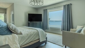 A bedroom with a bed, a TV, a sofa, and a view of the water. - Modern Lakeside Retreat on Lake Ontario 4+ bedroom/3 bath (Dexter)