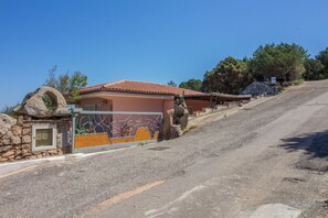 A residential property with a stone wall, a metal gate, and a house with a tiled roof.