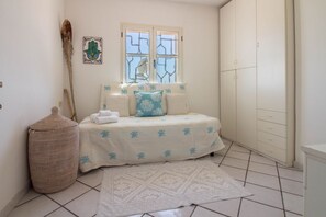 A bedroom with a bed, a window, a wardrobe, and a woven basket.
