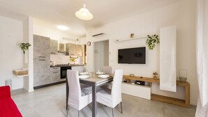 Een moderne keuken met een eethoek, een aan de muur bevestigde televisie en een rode bank.