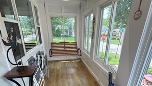 A room with a wooden bench, large windows, and a view of the outdoors. - Pristine 3-bedroom cottage in Lakeside, Ohio with central air, laundry, Wi-Fi (Lakeside)