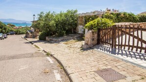 A paved street with a stone wall, a wooden fence, and a view of the sea. - GuestHost - Seaview Villa with Veranda GolfoAranci (Golfo Aranci)