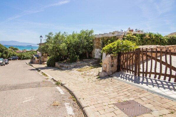 A paved street with a stone wall, a wooden fence, and a view of the sea.