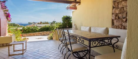 An outdoor patio with a table and chairs, a stone wall, and a view of the landscape.