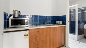 A compact kitchen with a microwave, sink, and wooden cabinets.