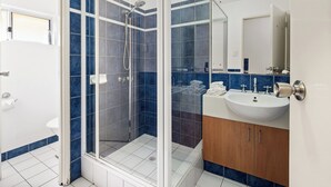 A modern bathroom with a glass shower enclosure, a sink, and a mirror.