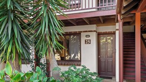 A building with a balcony, a wooden staircase, and a door marked with the number 25.