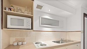 A kitchen with a microwave, a sink, and a dish drying rack. There are cabinets and a countertop.