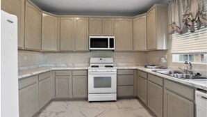 A kitchen with wooden cabinets, a microwave, a stove, and a sink.