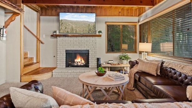 Una sala de estar acogedora con chimenea, techo de madera y un espacio de descanso cómodo.