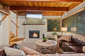 A cozy living room with a fireplace, wooden ceiling, and a comfortable seating area. - Timber & Tide Retreat + Fox Farm + Hot Tub + Games (Big Bear Lake)