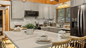 Una cocina moderna con armarios blancos, un refrigerador de acero inoxidable e una isla central con asientos.
