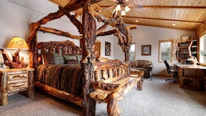 A rustic bedroom with a four-poster bed made of wood, a wooden desk, and a bookshelf. - Treetop Oasis| Hot Tub, Lake Views, AC & Game Room (Big Bear Lake)
