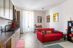 Eine moderne Küche mit einem roten Sofa und einem Esstisch im Wohnbereich.