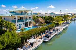 A waterfront property with a pool, boats docked along the pier, and a multi-story building with balconies.