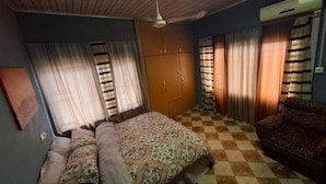 A bedroom with a bed, a wardrobe, a sofa, and a checkered floor. - Rankbel Holidays Apartment (Kumasi)