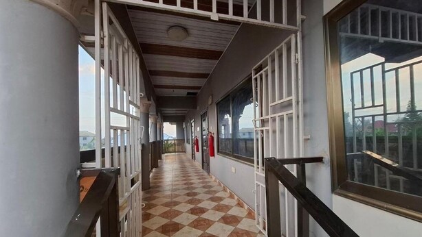 A corridor with checkered flooring, white railings, and large windows. - Rankbel Holidays Apartment (Kumasi)