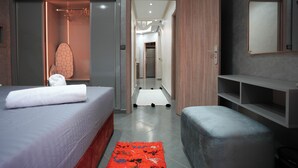 Ein modernes Hotelzimmer mit einem ordentlich bezogenen Bett, einer Sitzecke und einem Flur zu weiteren Zimmern.
