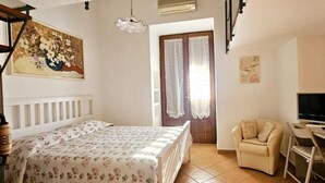 A bedroom with a bed, a chair, a desk, a TV, and a window with curtains. - Anthea Domus (Sorrento)