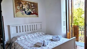A bedroom with a bed, a painting, and a balcony with a view of trees. - Anthea Domus (Sorrento)