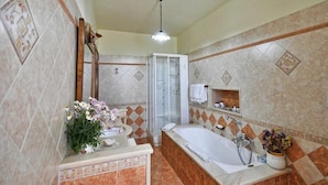 A bathroom with a large bathtub, a shower, and a vanity with a mirror. - Anthea Domus (Sorrento)