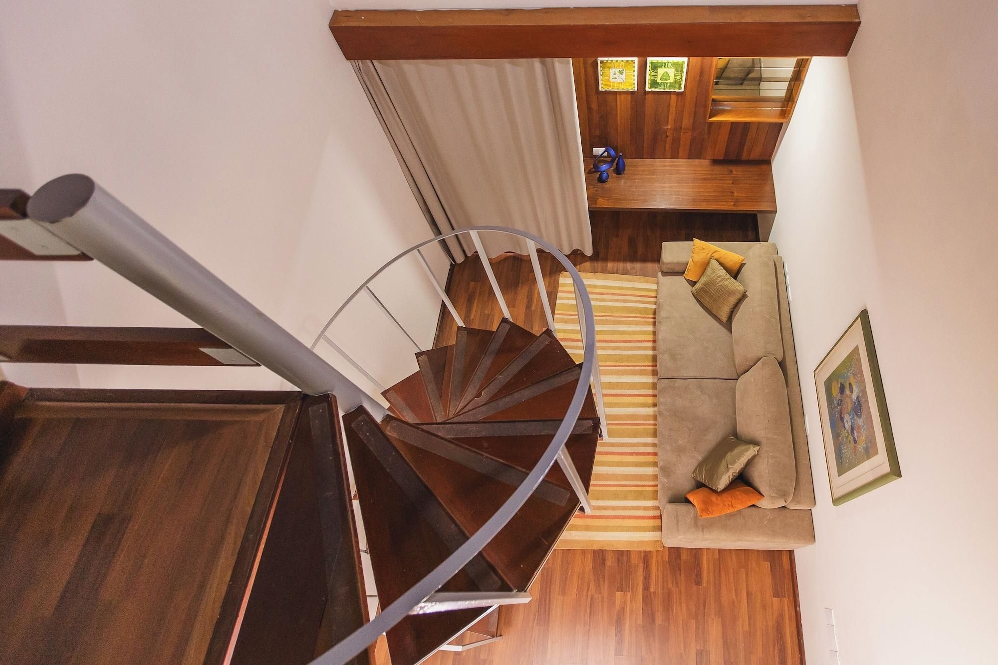 Una escalera de caracol conduce a una sala de estar con un sofá y cojines.