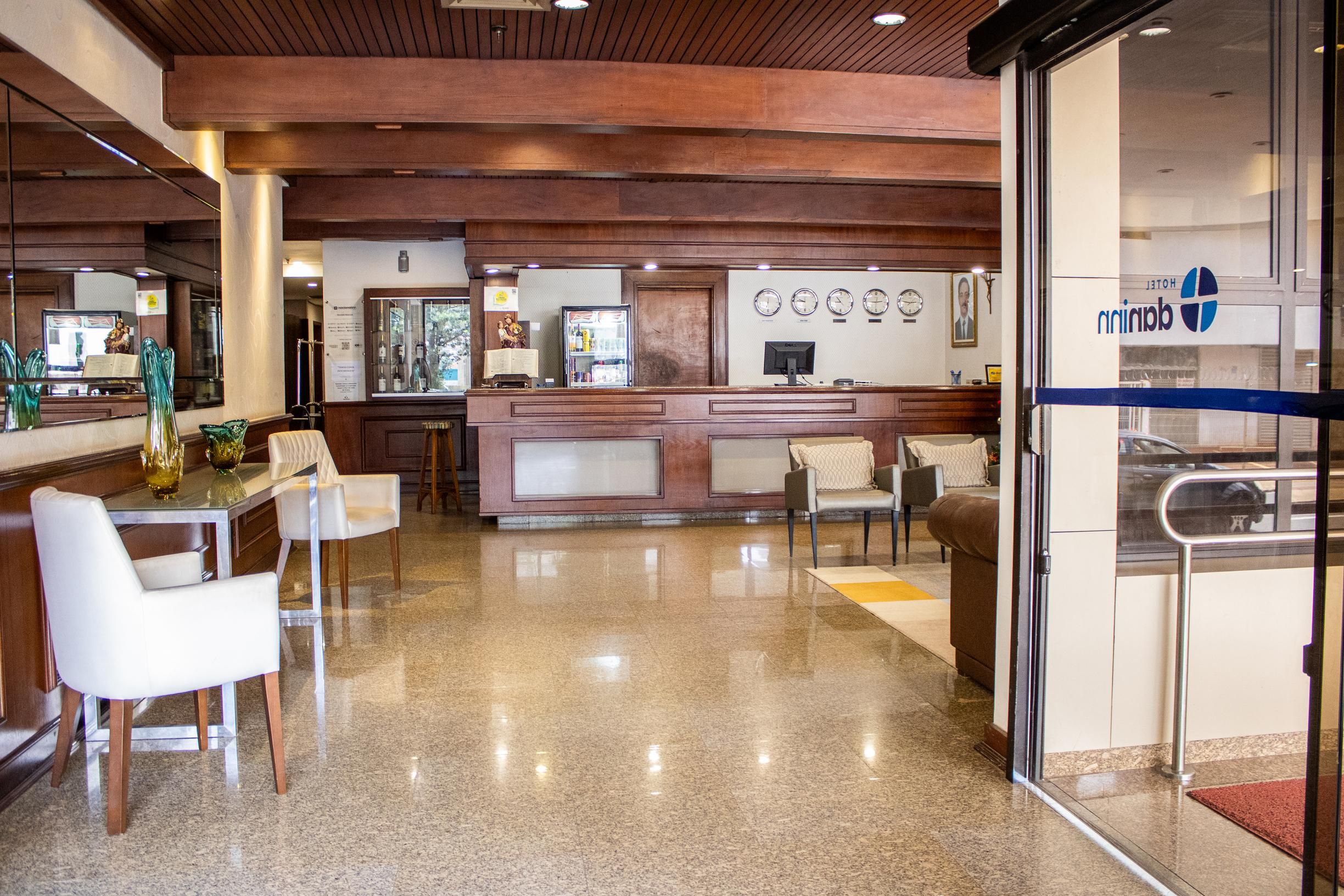 Um saguão de hotel com balcão de recepção, área de estar e divisória de vidro.