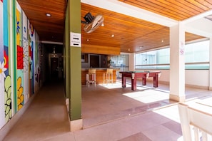 Un interior moderno con mesa de billar, zona de bar y un cartel que indica 'Sala C Academia'.