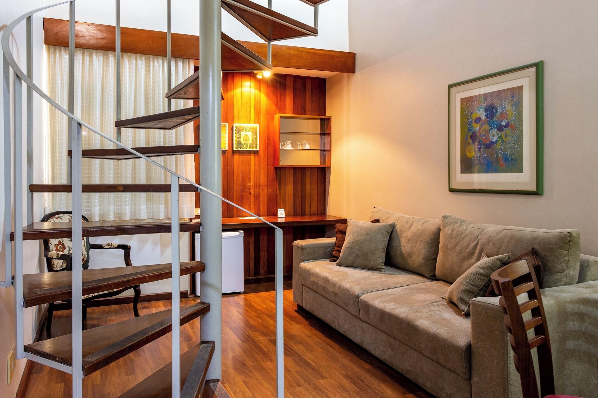 Un salon moderne avec un escalier en bois, un canapé et un tableau abstrait encadré.