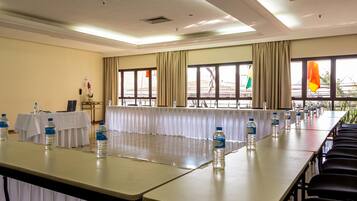 Un salón de conferencias con una larga mesa, sillas, botellas de agua y banderas.