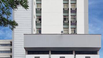Un edificio moderno con fachada plana, varios balcones y una serie de banderas en la planta baja.