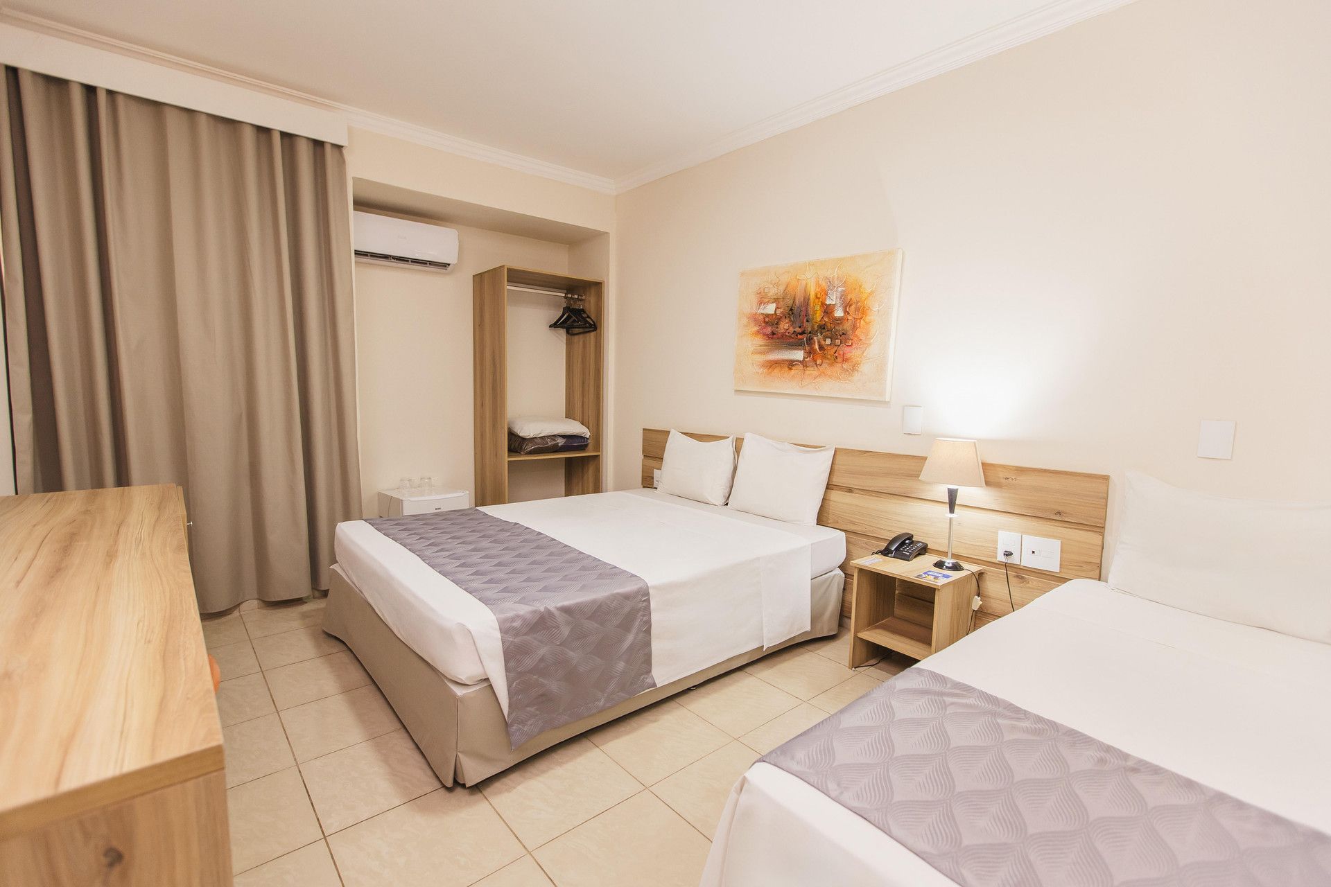 Una habitación de hotel con una cama, una mesita de noche, una lámpara y un cuadro en la pared.