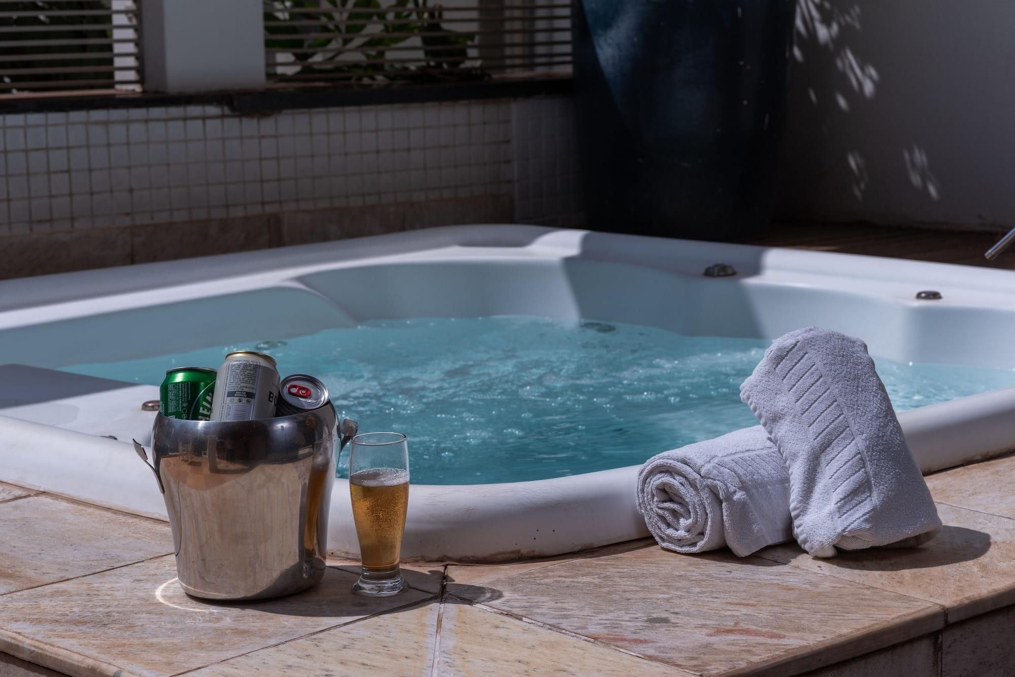 A hot tub with a towel and a drink bucket containing cans and a glass.