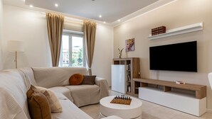 A modern living room with a sofa, a coffee table, a TV, and a bookshelf.