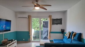 Ein Wohnzimmer mit Fernseher, Sofa und Deckenventilator.