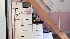 Ein Zimmer mit einer Holztreppe, weißen Stauraumeinheiten und zwei Pendelleuchten.