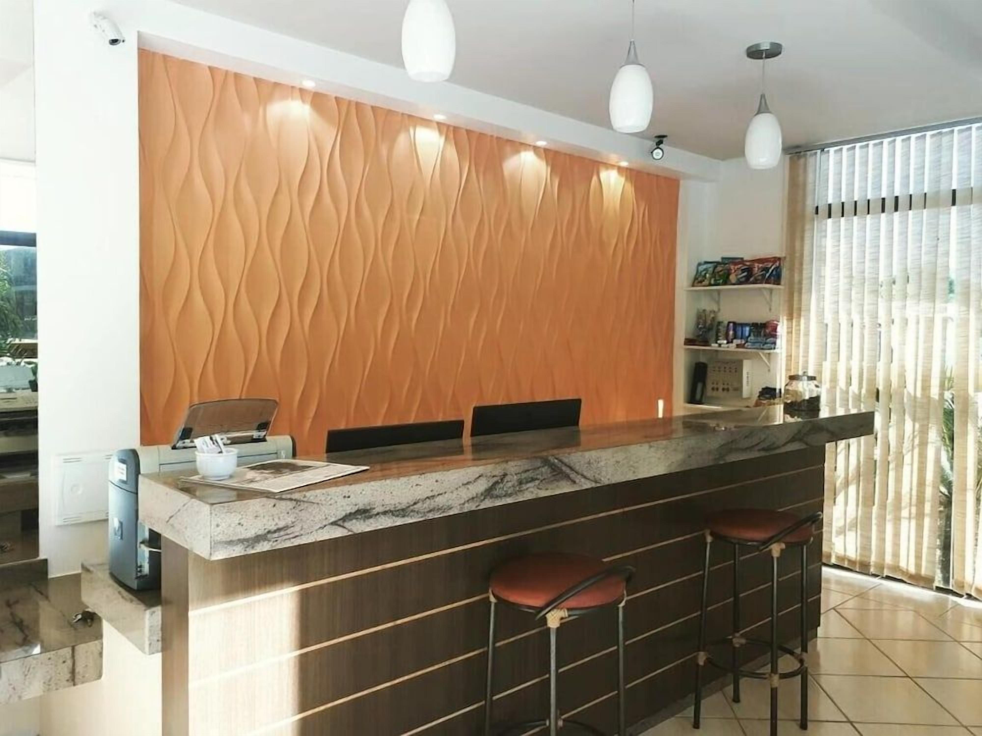 Cozinha moderna com bancada de mármore, painel de madeira atrás do fogão e banquetas.