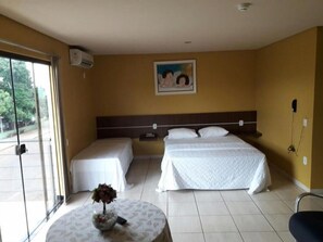 Une chambre d’hôtel avec deux lits, une petite table sur laquelle se trouve un vase, un tableau au mur et un appareil de climatisation.