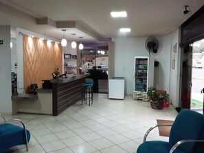 Un espace d’accueil comprenant un comptoir, des tabourets de bar, un réfrigérateur et un ventilateur.
