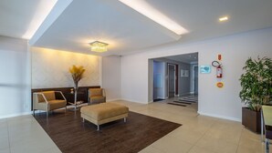 Un vestíbulo moderno con mostrador de recepción, zona de estar y una escalera que lleva a otras plantas.