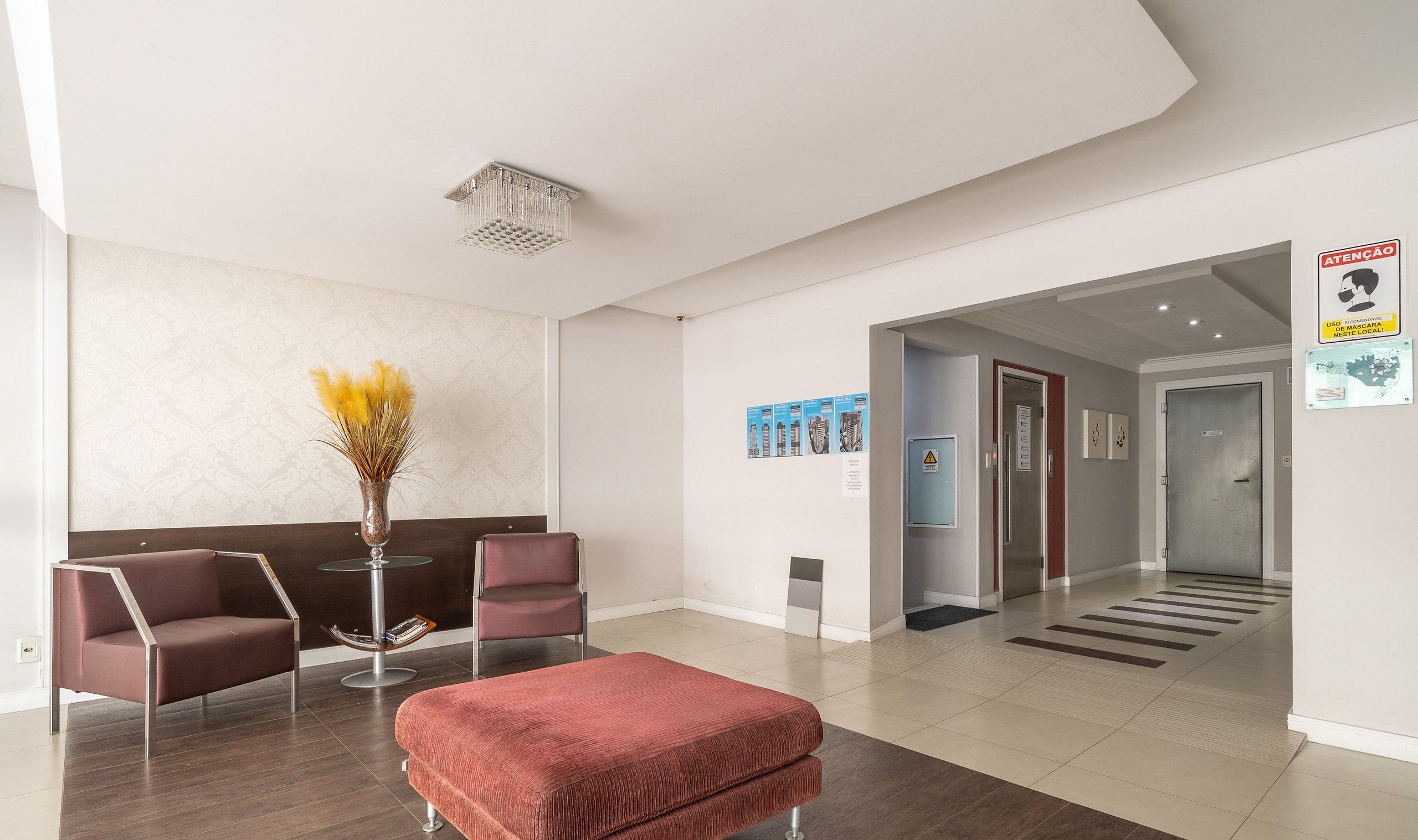 A modern reception area with a seating arrangement, a decorative vase, and a corridor leading to other parts of the building.