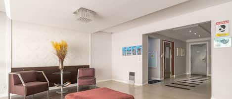 A modern reception area with a seating arrangement, a decorative vase, and a corridor leading to other parts of the building.