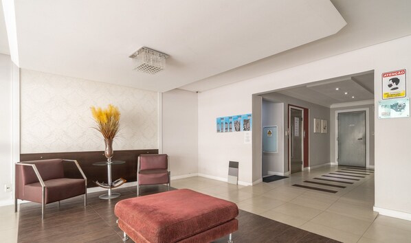 A modern reception area with a seating arrangement, a decorative vase, and a corridor leading to other parts of the building.