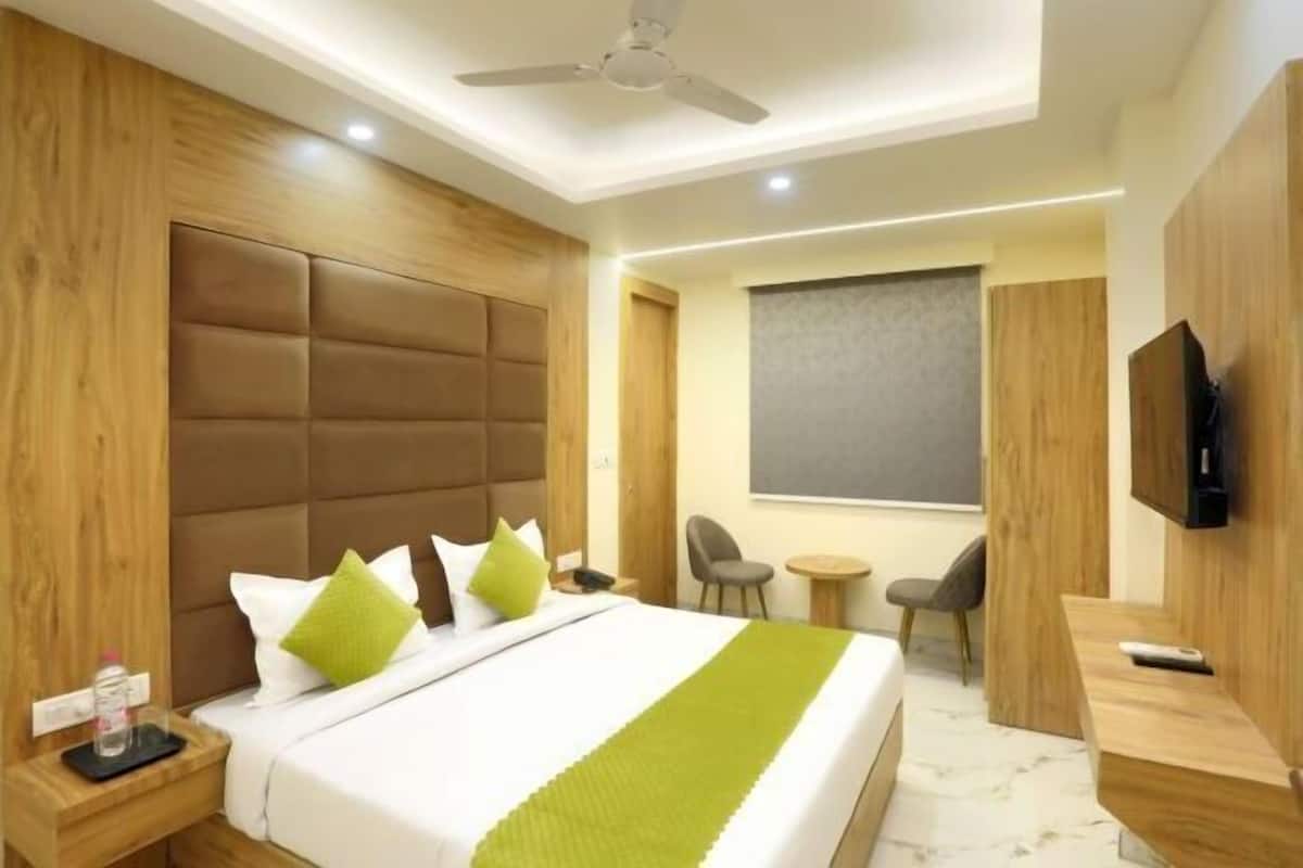 Una habitación de hotel con cama, televisor, escritorio, silla y una mesita.