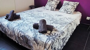 A bedroom with a large bed, purple walls, and a window.