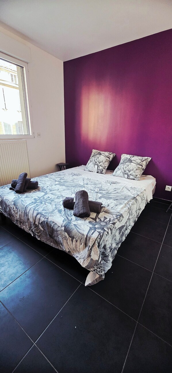A bedroom with a large bed, purple walls, and a window. - Hotel contro Marsiglia (Marseille)
