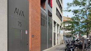 A building with "AVA 75" signage, a brick facade, and a parking area with motorcycles.